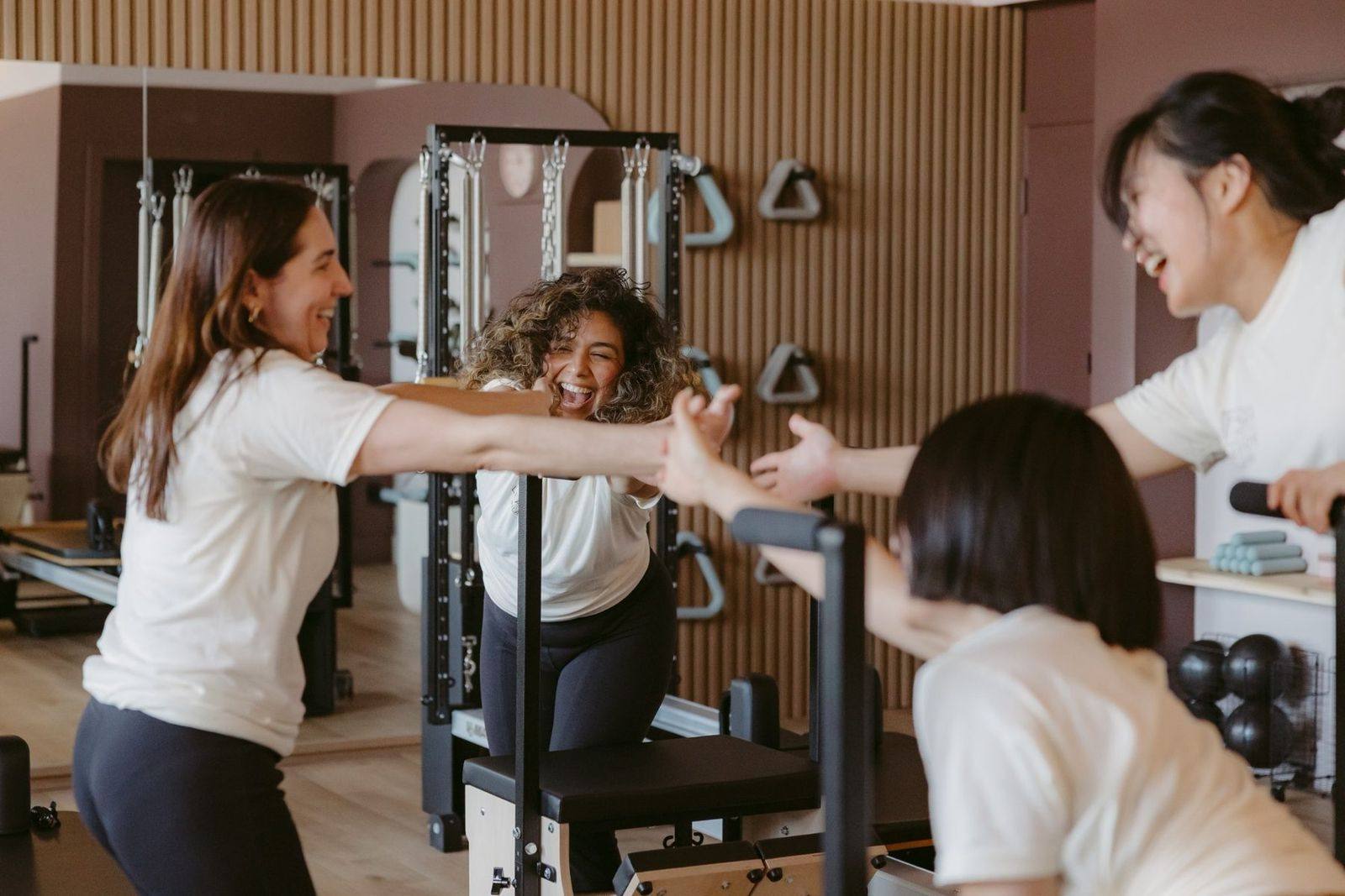 Leaside Pilates instructors sharing a joyful high-five in the studio